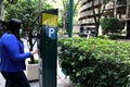 Latin adult woman with protection mask paying public parking on the street, new normal covid-19 Royalty Free Stock Photo