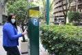 Latin adult woman with protection mask paying public parking on the street, new normal covid-19 Royalty Free Stock Photo