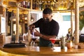 Latin American bartender with face mask working behind the bar in a modern cocktail bar