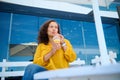 Latin American charming young adult woman drinking fresh healthy juice, sitting on a summer terrace of an outdoor cafe. Royalty Free Stock Photo