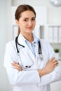 Latin american doctor woman standing with arms crossed and smiling at hospital. Physician ready to examine patient Royalty Free Stock Photo