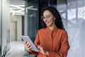 Latin american female programmer inside office standing near window using tablet computer for software testing and Royalty Free Stock Photo