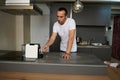 Latin American handsome man in white t-shirt and blue jeans, making fresh espresso in the modern minimalist kitchen Royalty Free Stock Photo