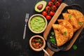 Latin American, Mexican, Chilean food. Traditional fried empanadas served with tomato and avocado sauce on a dark background. Top