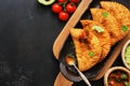 Latin American, Mexican, Chilean food. Traditional fried empanadas served with tomato and avocado sauce on a dark background. Top