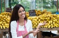 Latin american saleswoman at farmers market presenting bananas Royalty Free Stock Photo