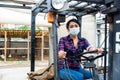 Masked hispanic woman sits behind the wheel of a tractor autocar during a pandemic. Royalty Free Stock Photo