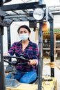 Masked hispanic woman sits behind the wheel of a tractor autocar during a pandemic.