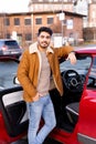 Latin or arab man leaned over near car with opened door on parking slot of city