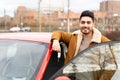Latin or arab man near car holding keys with opened door on city parking slot