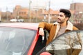 Latin or arab man near car holding keys with opened door on city parking slot