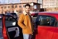 Latin or arab man standing near car with opened door on parking slot of city