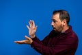 Latin bearded man dressed in a purple shirt isolated on blue studio background, he is throwing a kame hame imitating Son Royalty Free Stock Photo