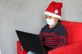 latin boy with protection mask and santa claus hat in video call with laptop, new normal covid-19 and christmas decoration Royalty Free Stock Photo