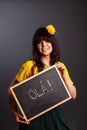 Latin brazil lady in a soccer clothes holding a small blackboard with Hello word on his native language isolated on gray