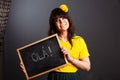 Latin brazil lady in a soccer clothes holding a small blackboard with Hello word on his native language isolated on gray