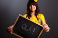 Latin brazil lady in a soccer clothes holding a small blackboard with Hello word on his native language isolated on gray