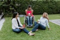 Latin business woman transgender on wheels chair and friends sitting on grass and meditating at terrace office in Mexico Latin Ame