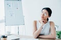 Latin businesswoman in glasses looking away while sitting at workplace