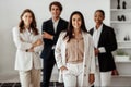 Latin businesswoman leader posing in office interior with her multiracial business team and smiling at camera Royalty Free Stock Photo