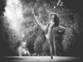 Latin dancer with leg raised in road full of vegetation monochrome