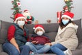 Latin family, grandmother, mom and child with protection mask and santa claus hat, christmas decoration, new normal covid-19 Royalty Free Stock Photo