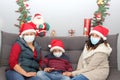 Latin family, grandmother, mom and child with protection mask and santa claus hat, christmas decoration, new normal covid-19 Royalty Free Stock Photo