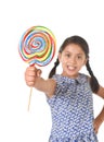 Latin female child holding huge lollipop happy and excited in cute blue dress and pony tails candy concept