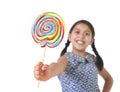 Latin female child holding huge lollipop happy and excited in cute blue dress and pony tails candy concept