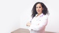Latin female doctor with serious attitude standing looking towards the camera in her office with stethoscope on her neck Royalty Free Stock Photo