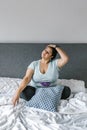 Latin girl plus size relaxing neck sitting on bed in Latin America, plus size woman