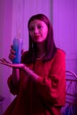 Latin girl in a red dress and red lipstick posing with a blue drink on a pink background with neon light Royalty Free Stock Photo