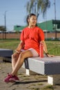 Latin girl in sportswear sitting on a bench in a public park