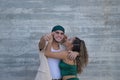 Latin and Hispanic boy and girl couple, young and nonconformist, embracing, while he makes a gun shape with hand pointing