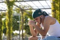 Latin and Hispanic boy, young, rebellious, with headscarf and hands intertwined praying, sitting on a bench, alone, sad and