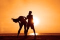latin hispanic couple is dancing bachata above sea on summer beach. Sunset over water.Two silhouettes against the sun. Just Royalty Free Stock Photo