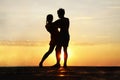 latin hispanic couple is dancing bachata above sea on summer beach. Sunset over water.Two silhouettes against the sun. Just Royalty Free Stock Photo