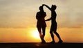 latin hispanic couple is dancing bachata salsa tango on summer beach. Sunset sky. 2 Two silhouettes against setting sun. Just Royalty Free Stock Photo