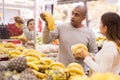 Latin man choosing sweet bananas and woman near helping him Royalty Free Stock Photo