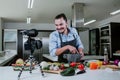 Latin man food blogger preparing mexican sauce, cooking and culinary skills concept. man shooting video of himself using camera on Royalty Free Stock Photo