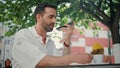 Latin man recording voice message at cellphone sipping coffee at street closeup