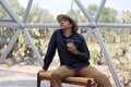 Latin man tourist with hat inside glamping room in mexico desert and drinking lemonade