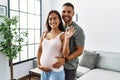 Latin man and woman couple hugging each other holding key of new house expecting baby at home Royalty Free Stock Photo