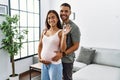 Latin man and woman couple hugging each other holding key of new house expecting baby at home Royalty Free Stock Photo