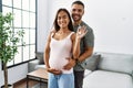 Latin man and woman couple hugging each other holding key of new house expecting baby at home Royalty Free Stock Photo