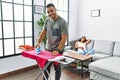 Latin man and woman couple ironing clothes while pregnant woman rest on sofa at home Royalty Free Stock Photo