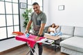 Latin man and woman couple ironing clothes while pregnant woman rest on sofa at home Royalty Free Stock Photo
