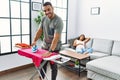 Latin man and woman couple ironing clothes while pregnant woman rest on sofa at home Royalty Free Stock Photo