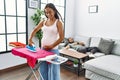 Latin man and woman couple ironing clothes while man rest on sofa at home Royalty Free Stock Photo