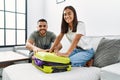 Latin man and woman couple smiling confident close travel suitcase at home